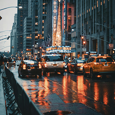 Mannhattan traffic in New York City in a rainy day next to the Radio City Building.