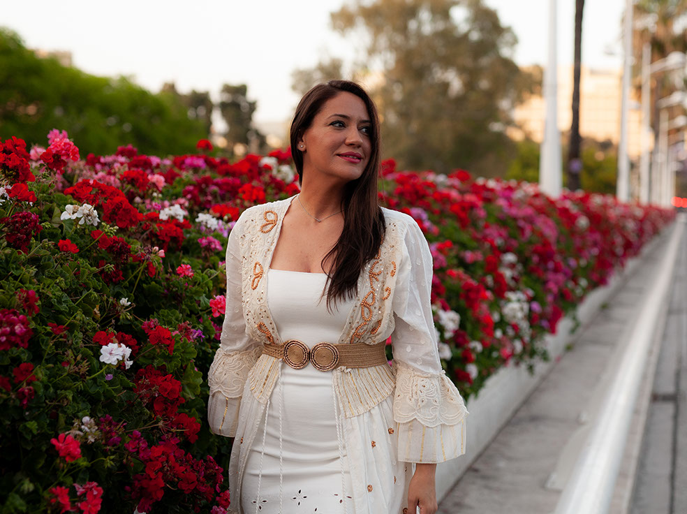 Girl in white dress among red flowers.