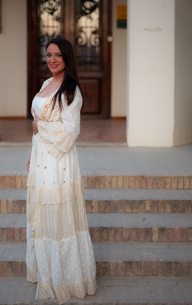 Girl in white dress standing on the stairs next to the house entrance.