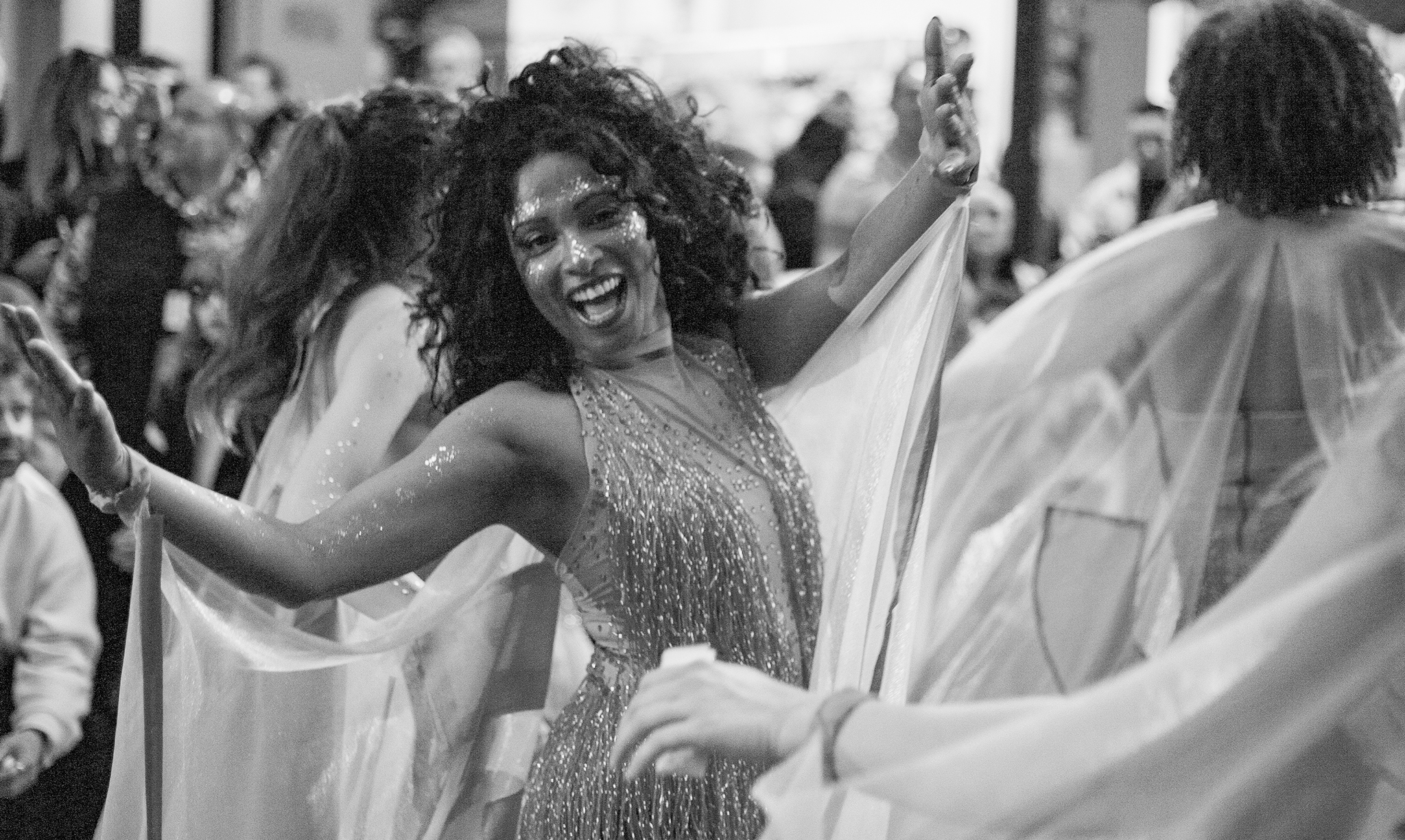 Black and white photo of a girl sending a kiss to a camera and her hands spread wide, smiling and excited